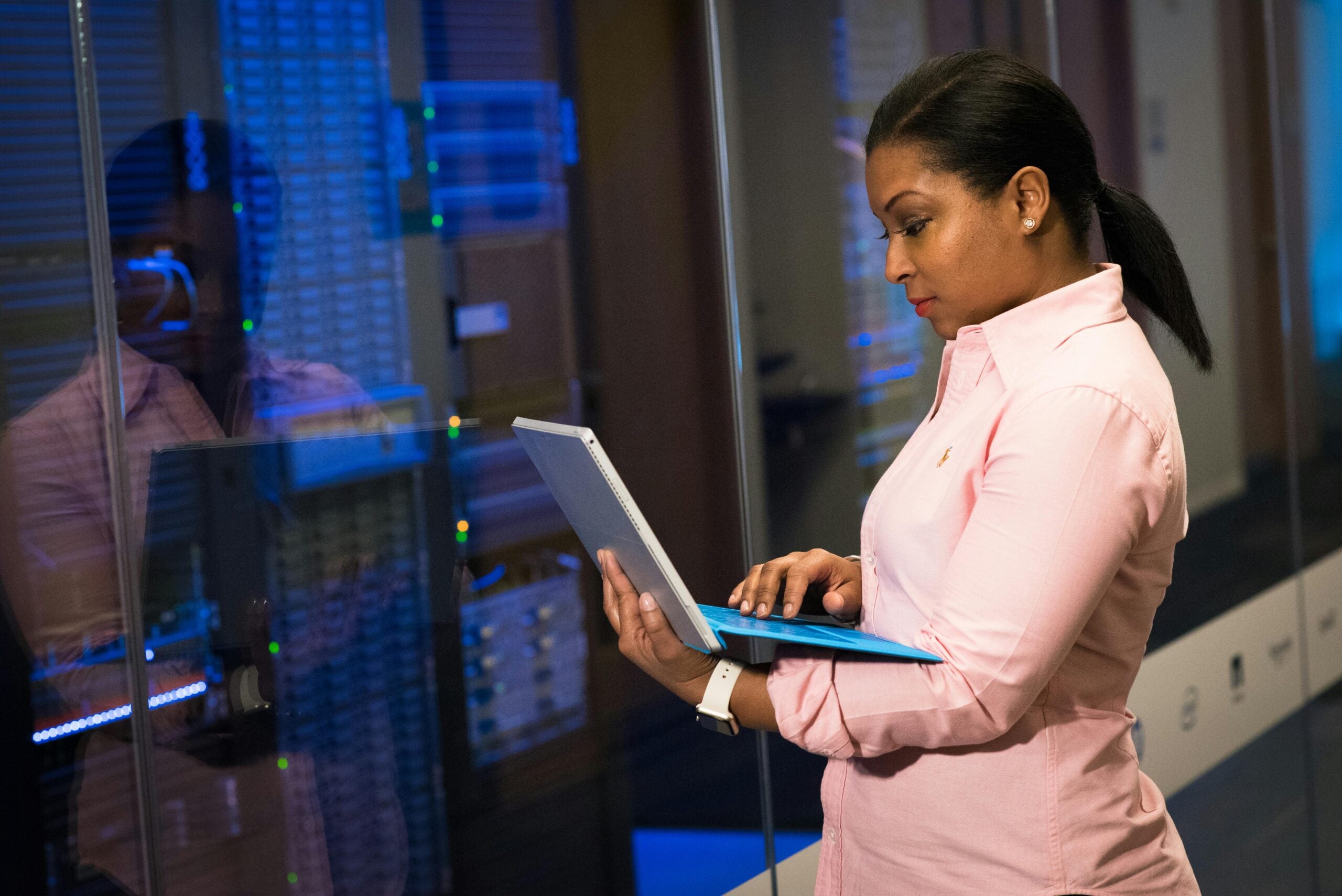 women with laptop in front of technology screen
